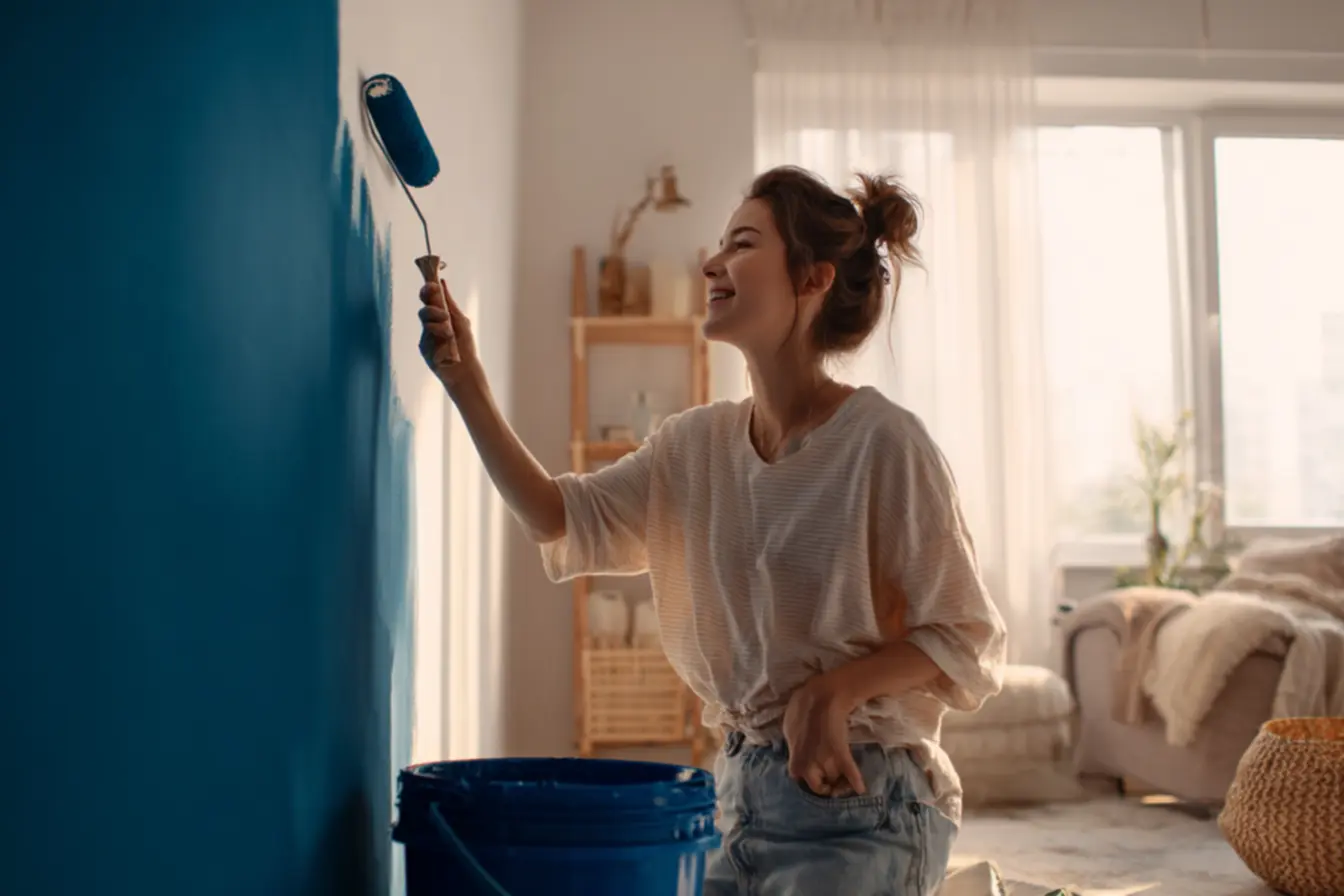 Diluindo a tinta e aplicando na parede com movimentos verticais.